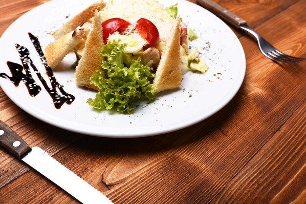 Insalata Caesar con condimento bianco e parmigiano in cima Tavolo servito per uno al ristorante o al bar Insalata di pollo, verdure e crostini su fondo di legno Concetto di cucina tradizionale