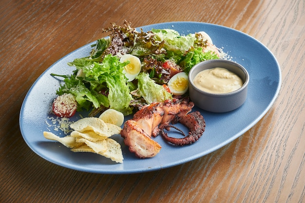 Insalata Caesar con crostini di pane, parmigiano, polpo, uovo in una ciotola bianca su superficie bianca. Servizio al ristorante. Primo piano con copia spazio.