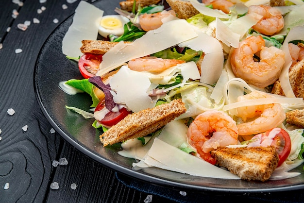 Insalata Caesar con gamberi alla griglia su sfondo scuro vista dall'alto