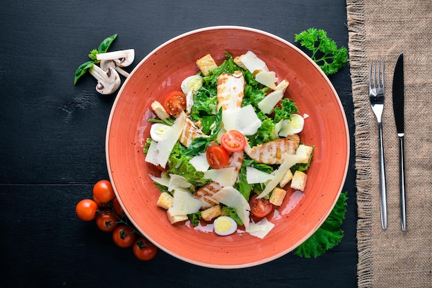 Insalata Caesar con pollo e verdure fresche Su uno sfondo di legno Vista dall'alto Spazio libero per il testo