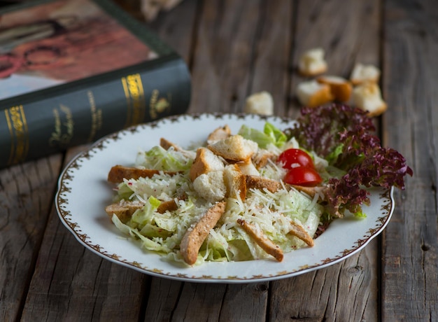 Insalata caesar di pollo fresca e sana servita in un piatto isolato su sfondo di legno vista laterale