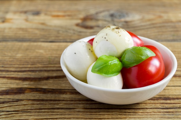 Insalata caprese con pomodori maturi e mozzarella con foglie di basilico fresco.