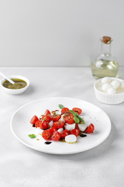 Insalata caprese con pomodori maturi mozzarella basilico fresco salsa balsamica pesto su piatto bianco