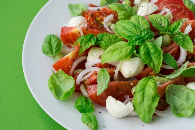 Insalata caprese con pomodorini freschi foglie di basilico bocconcini di mozzarella e cipolla