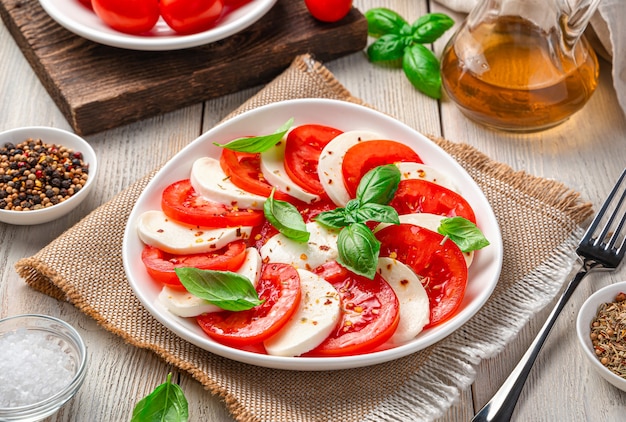 Insalata caprese estiva, leggera, italiana con pomodori, mozzarella, basilico e olio d'oliva. Primo piano di vista laterale.