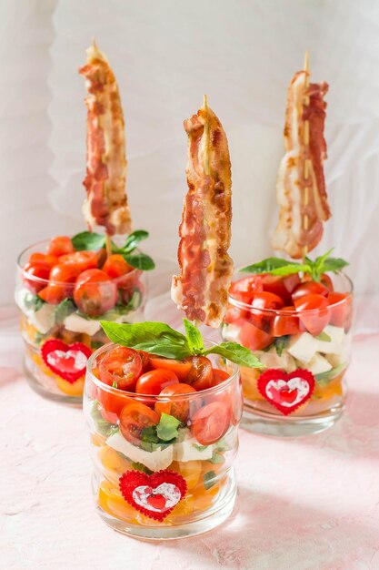 Insalata caprese festiva con pancetta fritta su spiedini in bicchieri