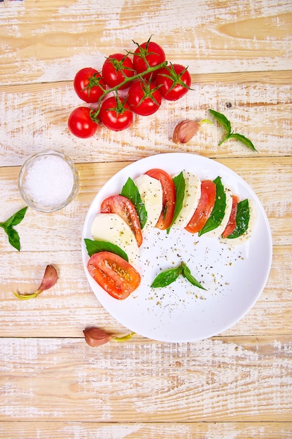 Insalata caprese italiana con fette di pomodoro, mozzarella, basilico, olio d'oliva.