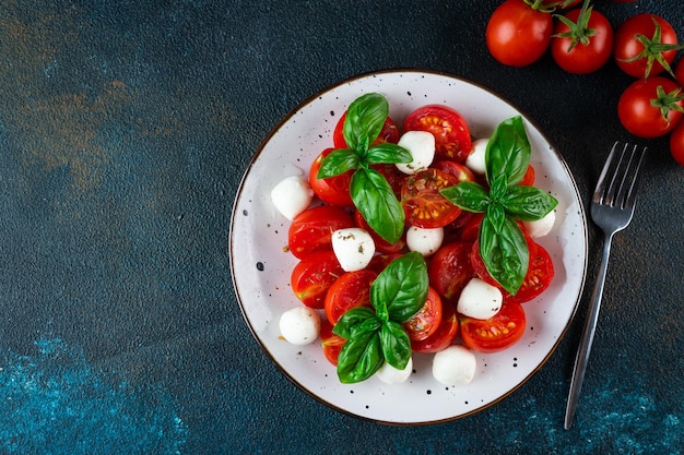 Insalata caprese italiana con pomodori a fette mozzarella basilico olio d'oliva su sfondo scuro Vista dall'alto Cibo italiano Insalata sana Cibo estivo