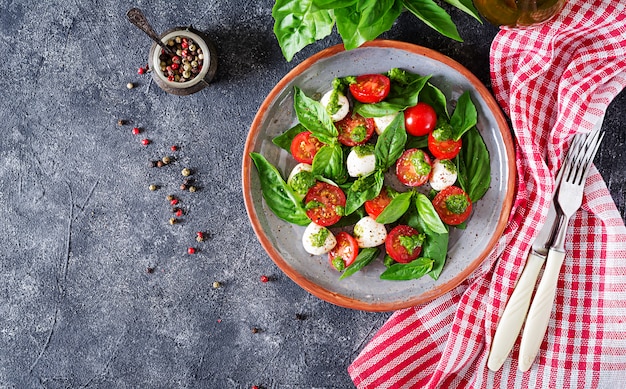 Insalata caprese. Pasto sano con pomodorini, palline di mozzarella e basilico. Cibo fatto in casa, gustoso. Concetto per un pasto vegetariano gustoso e salutare. Vista dall'alto. Disteso