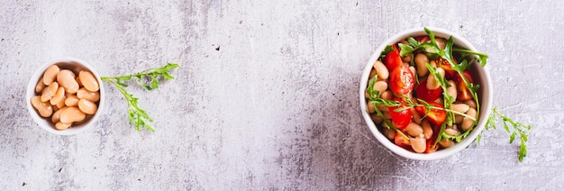 Insalata casalinga di fagioli bianchi, pomodori di ciliegio e arugula in una ciotola