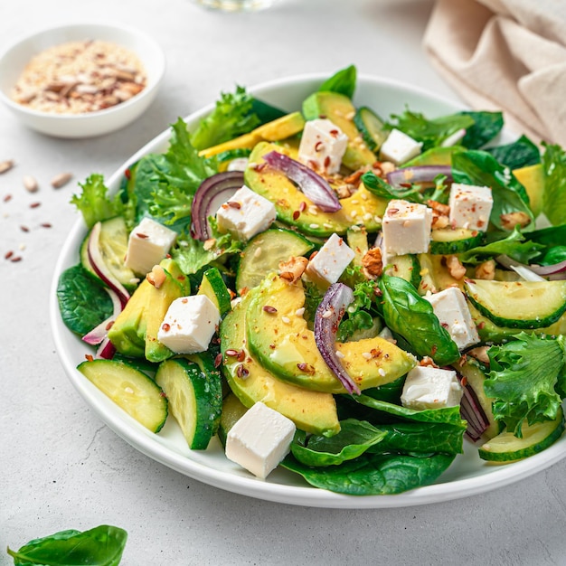 Insalata con avocado closeup Insalata vegetariana con feta di verdure e semi su sfondo grigio