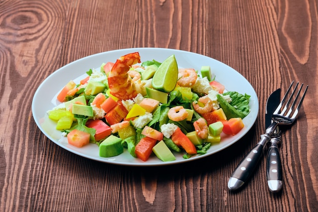 Insalata con avocado, feta e gamberi sulla vecchia tavola di legno