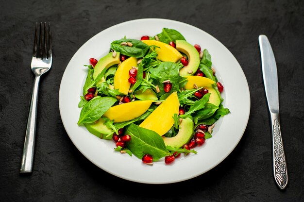 Insalata con avocado, rucola, spinaci, melograno, semi su uno sfondo di pietra