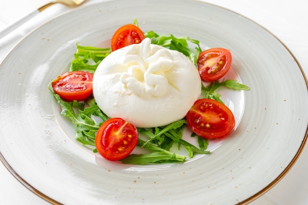 Insalata con burrata e pomodorini su fondo di legno bianco