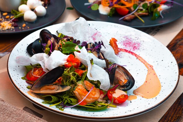 Insalata con cozze al forno gamberi alla griglia e chips di riso su un piatto