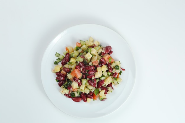 Insalata con fagioli, pomodori, cipolle, patate closeup sul piatto bianco. insalata di fagioli vista dall'alto isolata