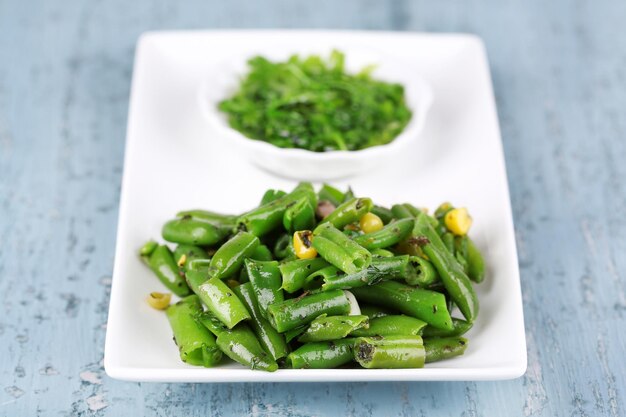 Insalata con fagiolini e mais con salsa sul piatto su fondo di legno di colore