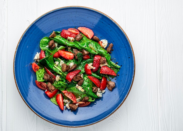 Insalata con fegato d'anatra fritto formaggio brie fragole pomodori e foglie di spinaci