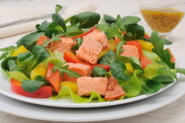 Insalata con fettine di radici di salmone rucola pomodori e peperoni conditi con salsa di senape