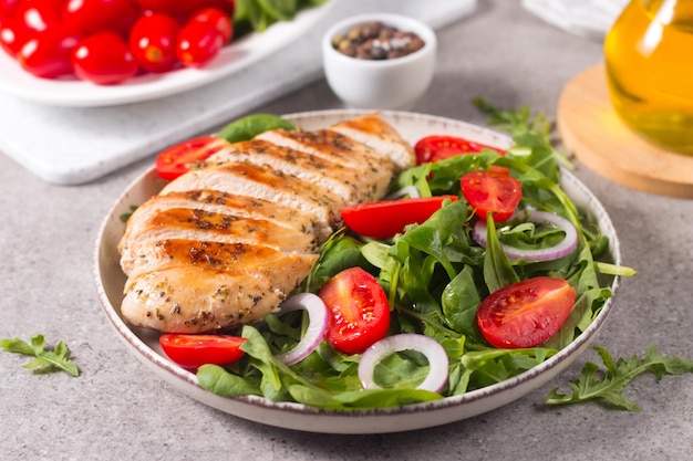 Insalata con filetto di pollo alla griglia, verdure fresche, spinaci, rucola, cipolla rossa e pomodoro.