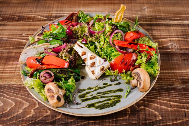 Insalata con formaggio, funghi e verdure su fondo di legno