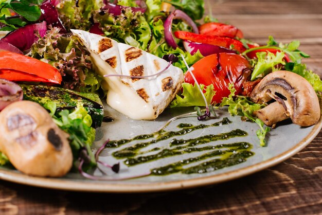 Insalata con formaggio, funghi e verdure su fondo di legno