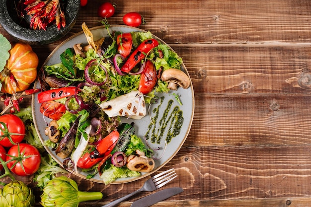 Insalata con formaggio, funghi e verdure su fondo di legno