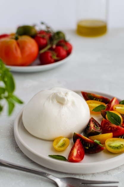 Insalata con formaggio italiano burrata, pomodori freschi maturi e basilico