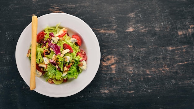 Insalata con formaggio, noci e verdure fresche. Su uno sfondo di legno. Vista dall'alto. Copia spazio per il tuo testo.