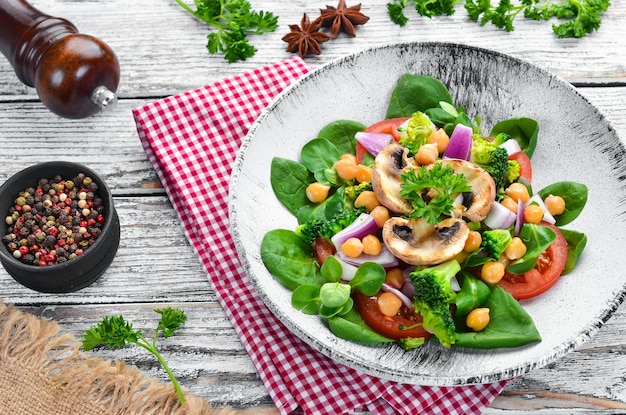 Insalata con funghi spinaci Piselli turchi e cipolla in un piatto su fondo di legno Vista dall'alto Spazio libero per il testo Disposizione piatta