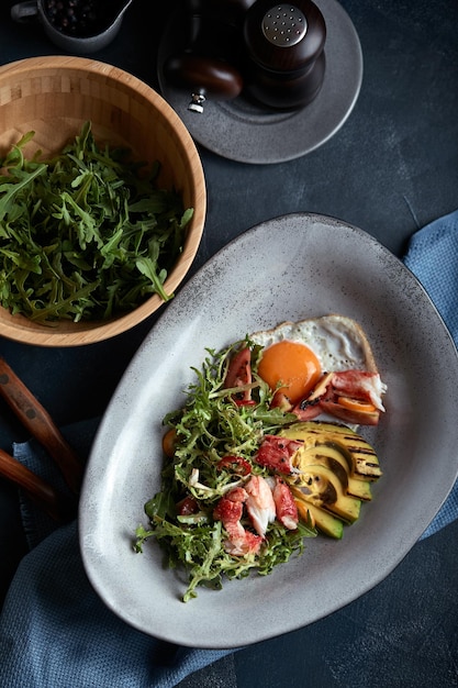 Insalata con granchio e avocado su fondo scuro Foglie di insalata di rucola condite con salsa su vino bianco con polpa di granchio e avocado grigliato in soft focus Vista dall'alto