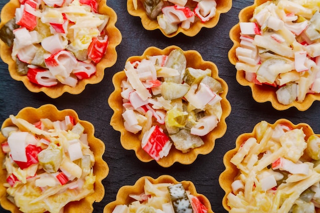 Insalata con granchio in tortine su sfondo nero primo piano.