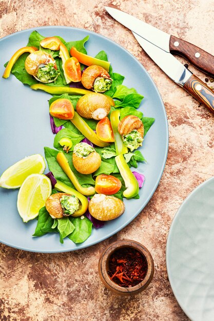 Insalata con lumache, spinaci, pomodoro e pepe. Insalata di verdure salutari