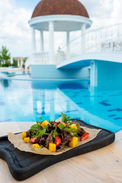 Insalata con mango di fragole di carne su una tavola di legno nera Resort di lusso