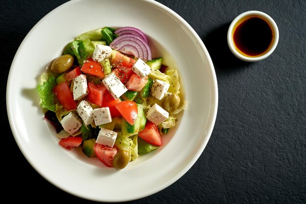 Insalata con olive, pomodori e feta in un piatto bianco. Insalata greca