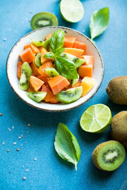 Insalata con papaya matura, kiwi, lime e sale su uno sfondo colorato, frutta tropicale appetitosa