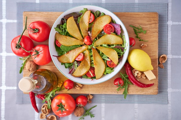 Insalata con pere pomodori e rucola su tavola di legno