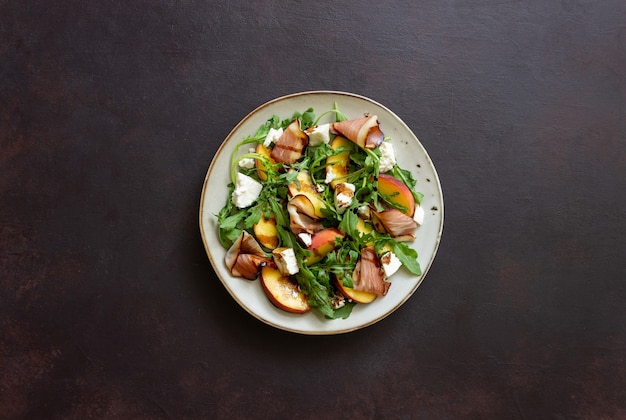 Insalata con pesche, rucola, formaggio e jamon. Mangiare sano.