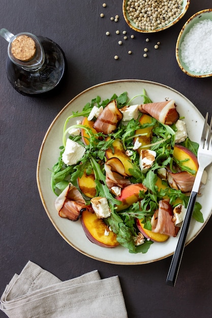 Insalata con pesche, rucola, formaggio e jamon. Mangiare sano.