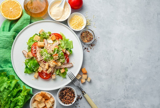 Insalata con petto di pollo, verdure fresche, formaggio e pangrattato su una scrivania grigia