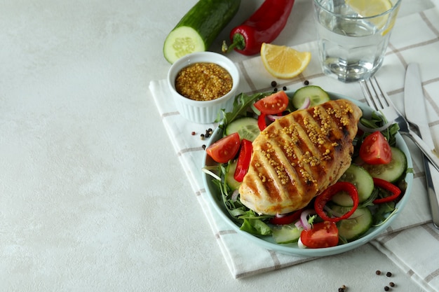 Insalata con pollo alla griglia sul tavolo strutturato bianco