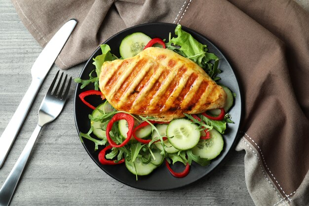 Insalata con pollo alla griglia sulla tabella strutturata grigia