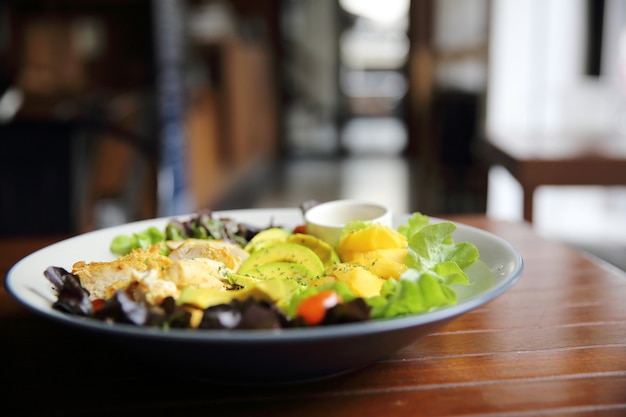 Insalata con pollo avocado e mango su fondo di legno