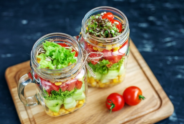 Insalata con pomodori e cetrioli e mais in un barattolo di vetro.