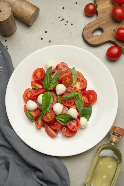 Insalata con pomodori mozzarella e basilico su sfondo grigio