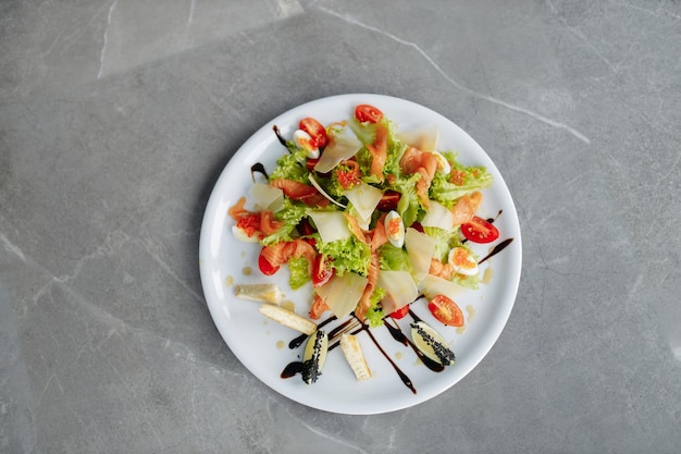 Insalata con pomodori uova salmone e caviale Deliziosa insalata al ristorante Foto su sfondo grigio Copia spazio