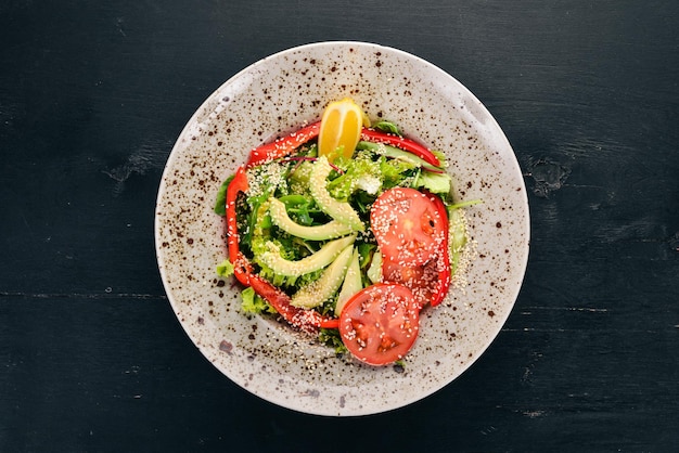 Insalata con pomodoro avocado e verdure fresche su sfondo di legno Vista dall'alto Spazio di copia