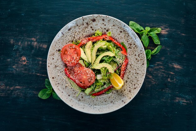 Insalata con pomodoro avocado e verdure fresche su sfondo di legno Vista dall'alto Spazio di copia