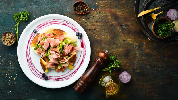 Insalata con prosciutto, brie e verdure su un piatto bianco. Vista dall'alto. Stile rustico.