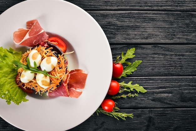 Insalata con prosciutto uova di quaglia prugne e verdure fresche sul piatto Su uno sfondo di legno Vista dall'alto Spazio libero per il testo